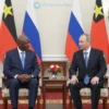 A formal portrait of Papua New Guinea Prime Minister James Marape meeting with Russian President Vladimir Putin. Both leaders are seated at a large table in a stately room, with flags of both countries subtly displayed in the background. The atmosphere is serious and diplomatic.
