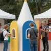 A vibrant and dynamic scene of interactive installations at a youth festival in Smolensk, Russia. The installations should be modern and engaging, featuring people of diverse ages and backgrounds interacting with them. Include elements of Russian culture subtly incorporated into the installations. The overall atmosphere should be joyful and energetic.