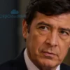 A portrait of a serious-looking man in a formal suit, reminiscent of a political figure. He should have a confident and slightly stern expression. The background should be blurred, suggesting an office setting. Focus on realistic skin texture and detailed suit fabric.