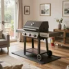 A cozy living room with a small, modern charcoal grill safely placed on a heat-resistant mat near a patio door. The room is well-lit with natural light and comfortable furniture. Focus on safety measures like a fire extinguisher nearby and a clear pathway around the grill.