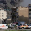 A photo-realistic image depicting the aftermath of explosions in Mykolaiv, Ukraine. Focus on damaged buildings, smoke, and debris. Include emergency vehicles (ambulances, fire trucks) responding to the scene. The overall tone should be somber and convey the impact of the explosions.