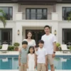 A family of four, including a father and three children, standing in front of a luxurious, modern house. The house should have a large garden and a pool. The family should appear happy and relaxed.