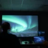 A group of Russian scientists in a modern laboratory, observing a large projection of the aurora borealis on a screen, with instruments and data displays, in a dimly lit, high-tech environment
