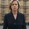 A serious-looking woman, Liz Truss, standing in front of a blurred background of the UK Parliament building. She is wearing a dark suit and a neutral expression. The overall mood should be somber and reflective.