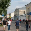 A vibrant street scene on Dzerzhinsky Street in Chelyabinsk, Russia during the late summer. The image should depict a mix of local businesses, people strolling, and perhaps some street performers. Focus on capturing the atmosphere of a typical summer day in the city.