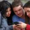 A photo-realistic image depicting a diverse group of young adults in the South Ural region of Russia, looking at a used car advertisement on a smartphone. The background shows a typical roadside scene with a slightly blurred landscape. Focus on conveying a sense of practicality and affordability.