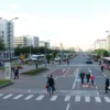 A cityscape of Volgograd with a focus on public spaces and infrastructure, showing people using designated areas appropriately. Include elements like parks, pedestrian zones, and public transportation to emphasize proper usage. The scene should be vibrant and orderly, with a clear depiction of urban life.