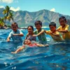 A group of schoolchildren pulling a struggling adult figure out of dark blue ocean water near a Hawaiian coastline, with tropical palm trees and volcanic mountains in the background, bright daylight, realistic human expressions of urgency and relief, no text or letters on the image