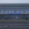 A wide shot of the Ulyanovsk airport terminal building on a Monday morning. The scene should depict a closed airport, with no airplanes on the tarmac and the terminal entrance appearing quiet or deserted. The lighting should suggest early morning, possibly with some fog or overcast skies to match the news context.