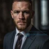 A realistic portrait of Conor McGregor, the famous MMA fighter, in a serious and contemplative mood, looking directly at the camera. He is wearing a suit and tie, symbolizing a formal and professional setting. The background is blurred to keep the focus on McGregor. The lighting is soft and natural, highlighting his facial features and expressions.