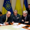 A group of Western officials and military personnel gathered around a table, discussing defense strategies. The table is covered with maps and documents related to air defense systems. In the background, a Ukrainian flag is visible, symbolizing the context of the discussion. The officials appear serious and concerned, reflecting the gravity of the situation.