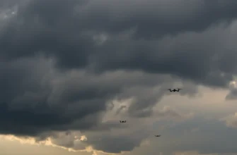 A dramatic sky over the Voronezh region with dark, ominous clouds and faint silhouettes of unmanned aerial vehicles (drones) visible in the distance, conveying a sense of aerial threat and tension, realistic atmospheric lighting, no text or symbols