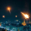 A nighttime scene depicting the defense of Moscow against an aerial drone attack. The image should show anti-aircraft defense systems in action, with missiles or projectiles being launched into the sky to intercept and destroy the drones. The scene should include the glow of explosions in the sky as the drones are being shot down. The cityscape of Moscow should be visible in the background, with buildings and skyscrapers illuminated by city lights. The overall atmosphere should convey a sense of