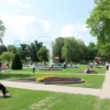 A vibrant park in Yaroslavl, Russia, named in honor of the 30th anniversary of Victory, showcasing well-maintained green spaces, walking paths, benches, and playgrounds. The park is bustling with people enjoying the outdoors, including families, children playing, and elderly individuals resting. The scene captures the essence of community and recreation, with trees, flowers, and possibly a small pond or fountain adding to the serene atmosphere.