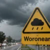 A stormy weather warning sign in Voronezh Oblast, with dark clouds, heavy rain, and wet streets, showing urgency without text or numbers