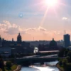 A sunny cityscape of Volgograd, Russia, with the Volga River prominently featured. The city should be depicted in a vibrant and detailed manner, showcasing its architectural landmarks. The overall mood should be calm and peaceful, reflecting the absence of a geomagnetic storm.