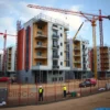 A modern residential construction site in the Chelyabinsk region of Russia with partially built houses, cranes, scaffolding, and workers in safety gear, showing the proportion of micro-apartments being constructed, realistic details, no text or numbers on image
