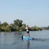 A tourist walking along the Volga River on a paddleboard, 165 kilometers journey, scenic landscape, clear sky, calm water, natural surroundings, peaceful atmosphere