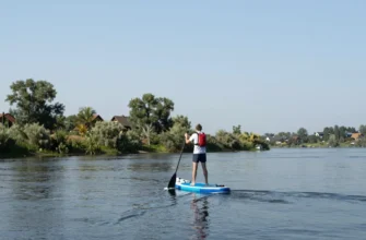 A tourist walking along the Volga River on a paddleboard, 165 kilometers journey, scenic landscape, clear sky, calm water, natural surroundings, peaceful atmosphere