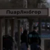 A realistic photo of a public bus stop in Yaroslavl, Russia, with the sign reading 'Машприбор', showing people waiting at the stop, urban street background, daytime lighting, clear signage