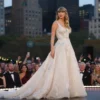 Taylor Swift standing on a stage in New York City, wearing an elegant wedding dress, surrounded by a crowd of guests, with a city skyline and festive decorations in the background, soft lighting, joyful atmosphere