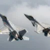 A dramatic aerial scene showing a Chinese J-16 fighter jet and a Russian Su-35 fighter jet both blocking a US F-35 aircraft in mid-air, with clear national markings and realistic military aircraft details, set against a cloudy sky background