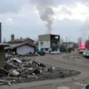 A damaged civilian infrastructure in Engels, Russia, showing the aftermath of an attack. The scene should depict destroyed buildings, debris, and possibly emergency services responding to the situation. The image should convey a sense of devastation and urgency.