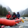 Five people lost in a remote river rafting expedition in the Magadan region, surrounded by dense taiga forest, rugged mountains, and a fast-flowing river, with overcast sky and misty atmosphere, wearing outdoor gear and holding emergency equipment