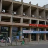 A realistic photograph of a partially constructed or abandoned market building in a Russian city, showing signs of halted construction such as exposed concrete, scaffolding, or unfinished structures, with a somber atmosphere reflecting financial difficulties, no text or signs visible