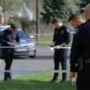 A photo-realistic image depicting a police investigation scene in a suburban area of the Moscow region. Several police officers are examining a crime scene with evidence markers. A police car is visible in the background. The overall atmosphere should be serious and investigative.