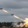 A dramatic sky over the Leningrad region with anti-aircraft missile launchers firing at several small Ukrainian drones, explosions and smoke trailing from the intercepted drones, distant silhouettes of pine forests and a faint outline of a city skyline on the horizon, realistic lighting and atmospheric clouds