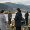 A solemn and respectful scene depicting a memorial or tribute for the missing girls in Tuva. The image should show a group of people gathered in a natural setting, perhaps near a river or mountains, holding candles or flowers. The atmosphere should be serene and reflective, with soft lighting and muted colors to convey a sense of peace and remembrance.