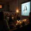 A solemn evening memorial event in Smolensk honoring the late poet Raissa Ibragimova, featuring a quiet gathering of people with candles and flowers at a cultural venue, soft ambient lighting, respectful atmosphere