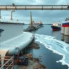 A modern dairy processing facility in Ulyanovsk with milk flowing like a river through pipelines and tanks, symbolizing export success, featuring Russian flag elements and export cargo ships on a river background, photorealistic style