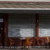A closed restaurant in Kostroma with shutters down, empty tables, and a 'Closed for 3 months' sign on the door, showing signs of disuse and quiet surroundings