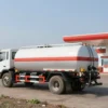 A fuel truck delivering fuel to a gas station in a rural area of the Ulyanovsk region. Focus on the truck and the gas station, with fields and a clear sky in the background. The scene should convey a sense of essential service and support for the local community.