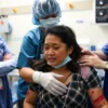 A woman in distress, with visible injuries, being comforted by medical professionals in a hospital setting. The scene should convey a sense of urgency and care, with the woman's face blurred to protect her identity. The background should include medical equipment and a sterile environment.