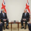 A formal diplomatic meeting between British and Iranian officials in a neutral location. The scene should convey seriousness and diplomacy. Focus on the body language and expressions of the individuals. Include flags of both countries subtly in the background.