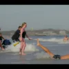 A great white shark lunging out of the water to bite a swimmer's leg on a crowded New York beach, with lifeguards and other beachgoers reacting in shock, sunlit shoreline, city skyline in the distance, realistic details, no text or letters on the image