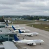 A wide shot of Yaroslavl Airport, showing the airport terminal and runways. The sky is overcast. Several airplanes are visible on the tarmac. The overall mood is one of disruption and closure.