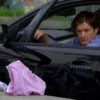 A chaotic scene depicting a drunk driver in a car, with discarded underwear on the ground. The car is parked on a street. Focus on the driver's distressed expression and the surrounding environment.