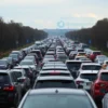 A long line of 1200 cars stretching towards the Crimean peninsula, under a cloudy sky. The cars are various models and colors, indicating a large number of vehicles. The scene should convey a sense of congestion and the scale of the traffic jam.