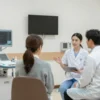 A specialized neurology clinic room in a central hospital, equipped with modern medical devices, comfortable seating for patients, wall-mounted diagnostic monitors, and a professional healthcare provider in a white coat consulting a patient. The room is clean, well-lit, and calm, with neutral tones and minimalistic design to promote a soothing environment.