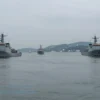 A modern maritime scene showing a narrow strait with calm waters, featuring ships and coastal landscapes, possibly with subtle signs of naval activity or cooperation, no text or symbols on the image