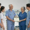 A group of medical professionals in a hospital setting, receiving a symbolic check or certificate for their adoption or guardianship. The scene should depict a warm and supportive atmosphere, with colleagues congratulating and celebrating the event. The medical professionals should be wearing scrubs or medical attire, and the setting should include typical hospital elements like medical equipment and supplies in the background.