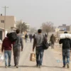 A somber scene of Palestinian families carrying minimal belongings walking away from a modest urban neighborhood under a hazy sky, suggesting economic hardship and migration due to poverty rather than conflict, with subtle visual cues like empty shops, worn clothing, and distant barren landscapes, emphasizing quiet desperation over violence