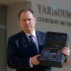 A man in a business suit standing in front of a modern courtroom building in Yaroslavl, holding a broken ATM terminal with wires exposed, stern expression, dramatic lighting, realistic details, high resolution