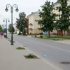 A street view of a residential area in Yaroslavl, Russia, showing a newly renovated street with clean sidewalks, modern street lamps, fresh pavement, and greenery. Include people walking or enjoying the improved environment, with a sense of community and urban renewal. The scene should reflect a peaceful, well-maintained neighborhood during daytime.