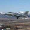 A modern fighter jet soaring over a vast landscape of Russia, with snow-capped mountains in the background and a clear blue sky. Include elements like a radar tower and a distant city skyline to emphasize advanced aviation capabilities.