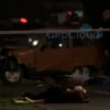 A realistic photograph of a somber scene in Yaroslavl region showing a young woman in her early twenties lying on the ground near a damaged car after a traffic accident, emergency lights flashing in the background, police tape and investigators present, somber atmosphere, muted colors, no text or symbols